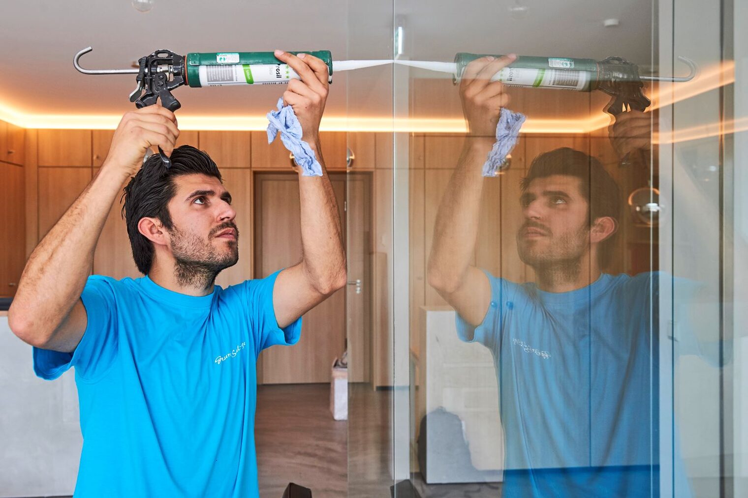 Glaser mit einer Kartusche verklebt eine Glasscheibe