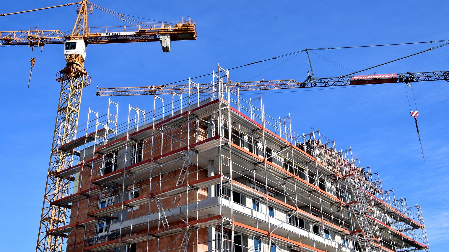 Baustelle eines mehrstöckigen Wohnhauses mit zwei Kränen