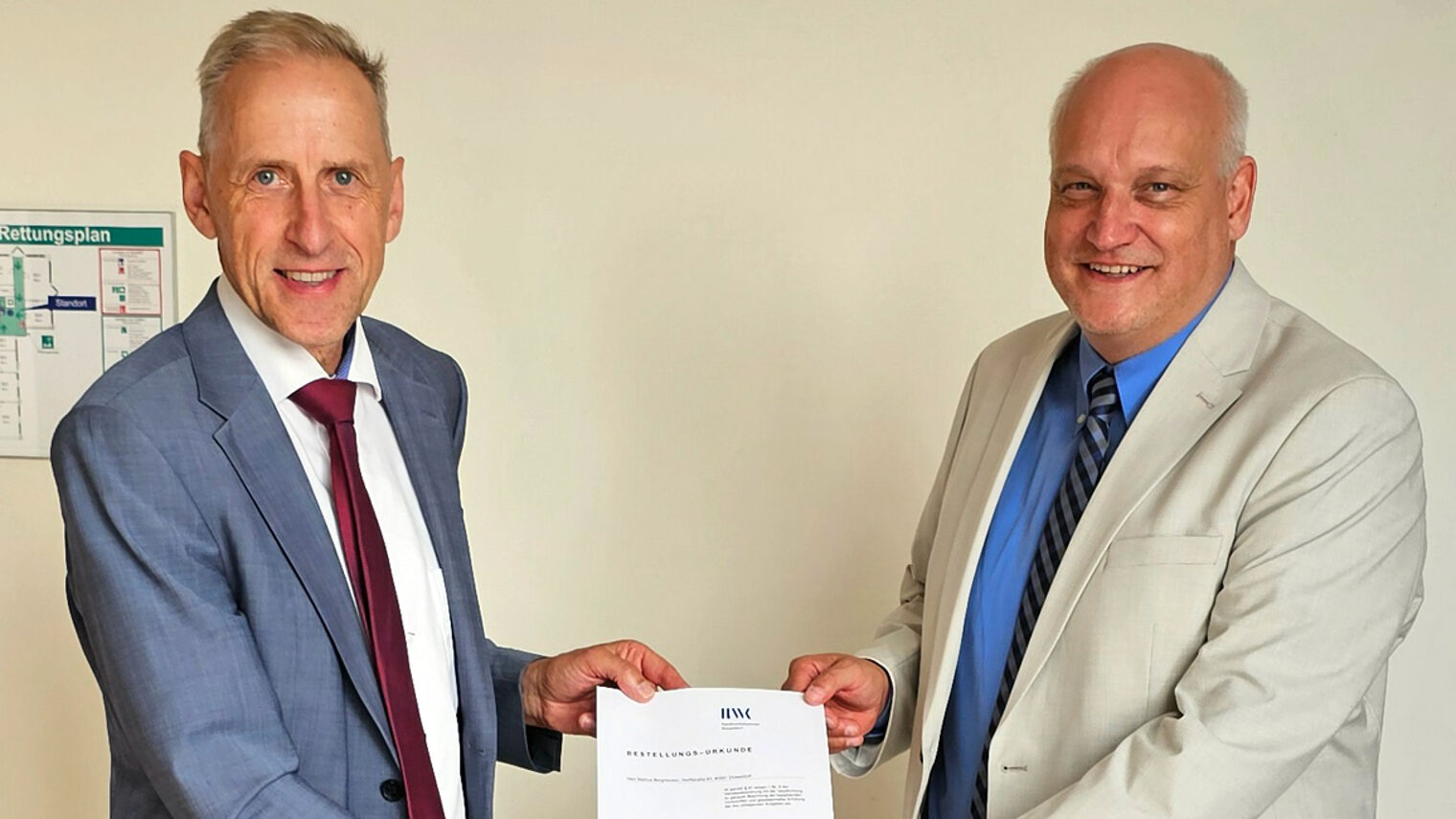 Dr. Axel Fuhrmann und Makus Berghausen halten die Vereidigungsurkunde in die Kamera.