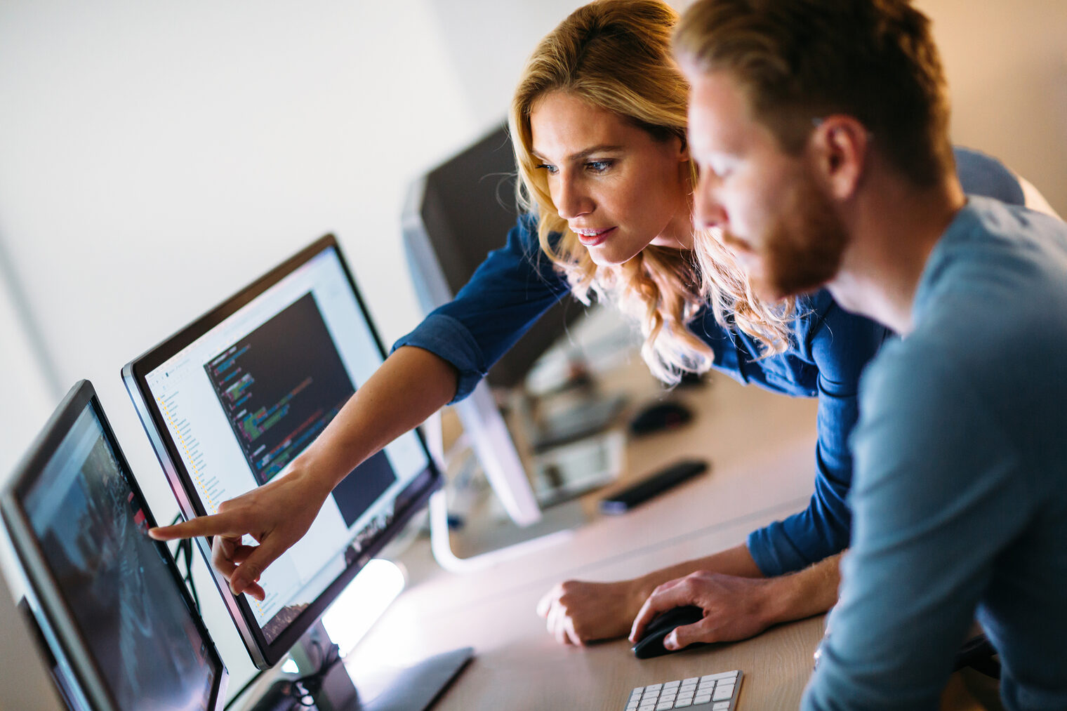 Eine Frau und ein Mann arbeiten gemeinsam am Computer an einem Projekt.
