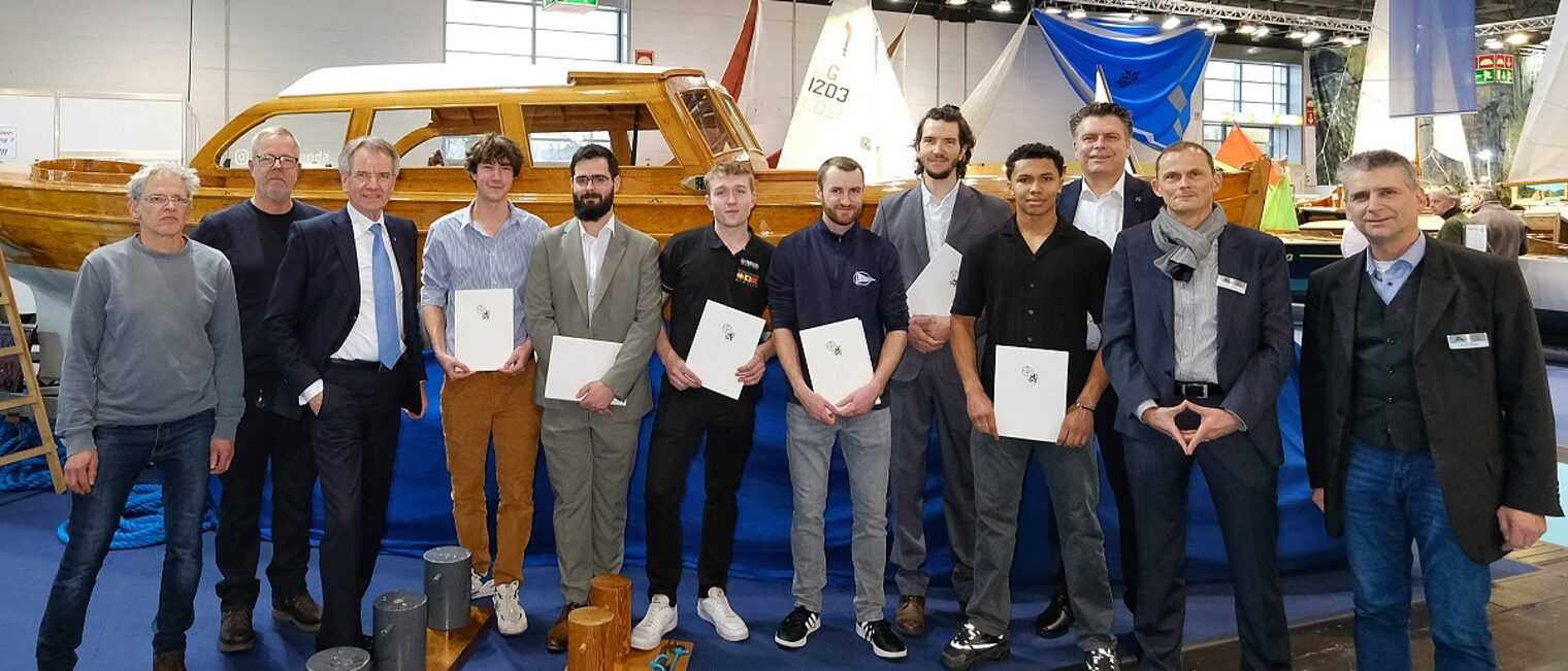 Lossprechung Bootsbauer 24.01.2025 Die Teilnehmer stehen auf der Messe boot 25 vor einem ausgestellten Schiff.