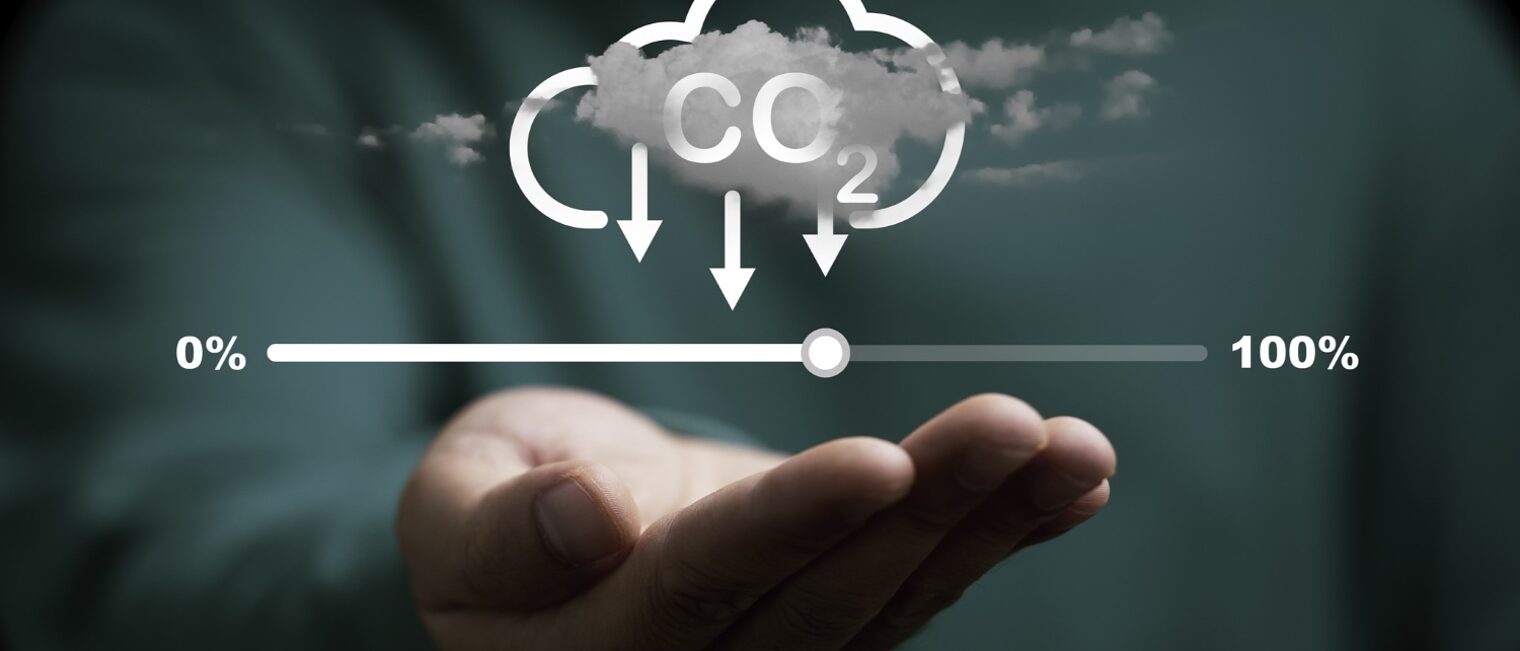Über einer Hand schwebt ein Kohlenstoff-Reduktionssymbol mit Wolke und Ladebalken für Null-Emissionen.