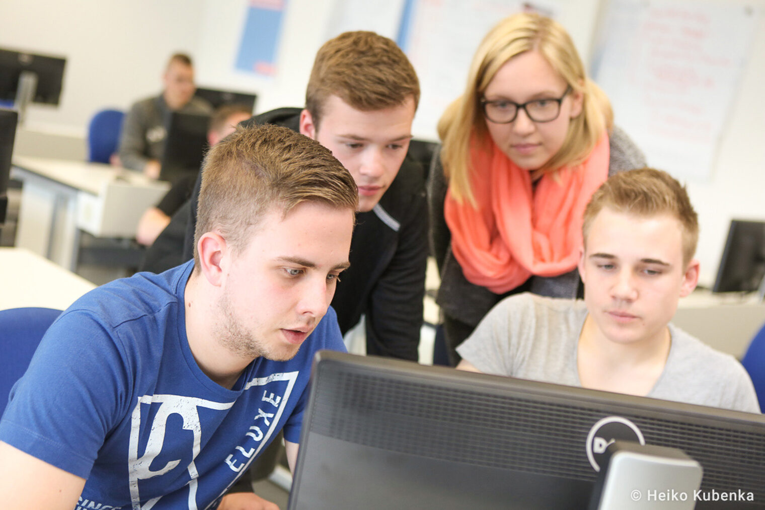 Teamarbeit im Seminar – Teilnehmer diskutieren eine Aufgabe am Computer Gruppe von jungen Erwachsenen arbeitet gemeinsam an einem Computer