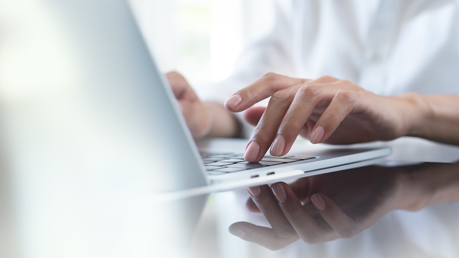 Nahaufnahme von Händen, die an einem Laptop tippen