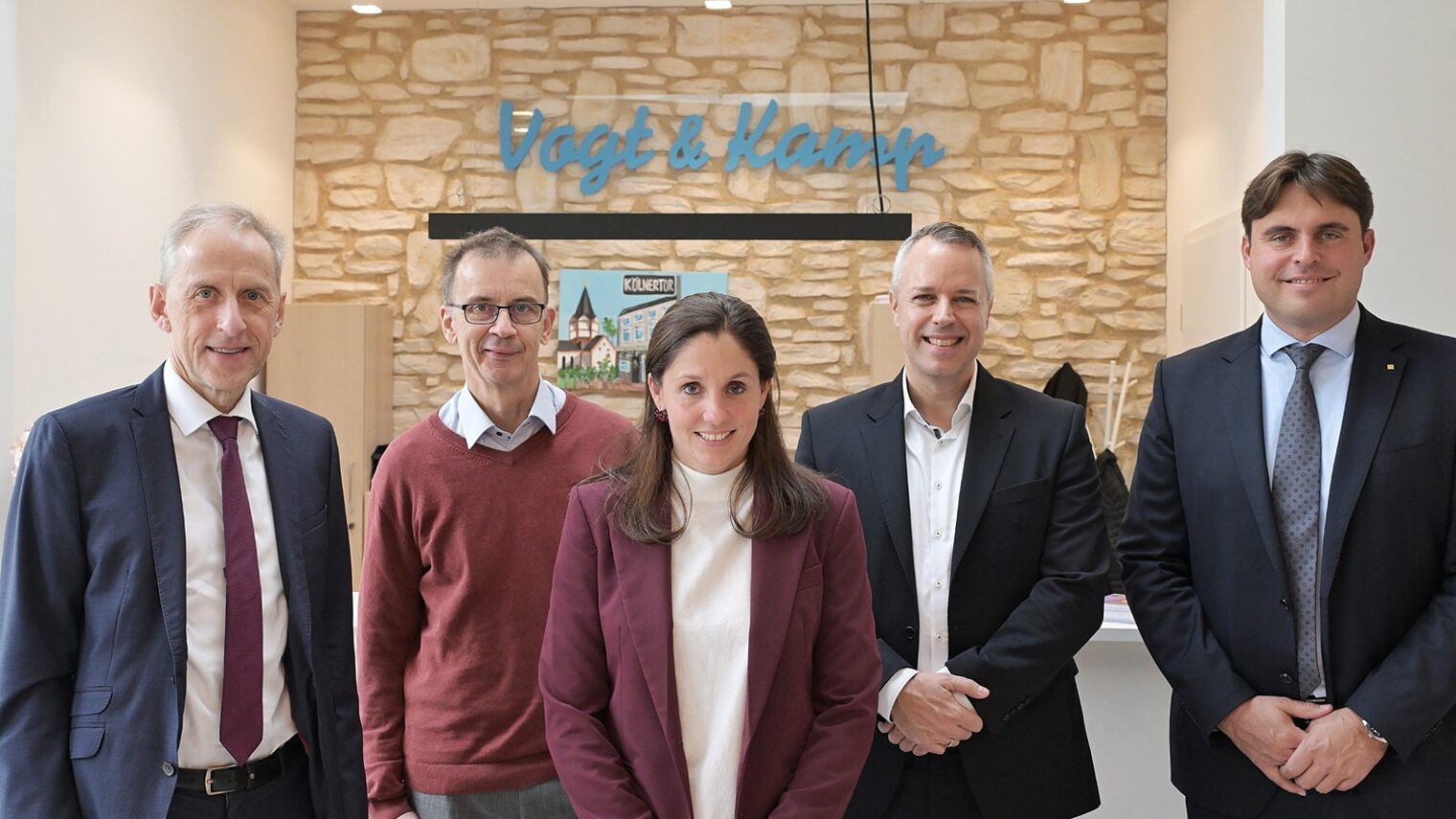 Die Teilnehmer der Pressekonferenz posieren vor einem Hintergrund in Backsteinoptik für ein Pressefoto.
