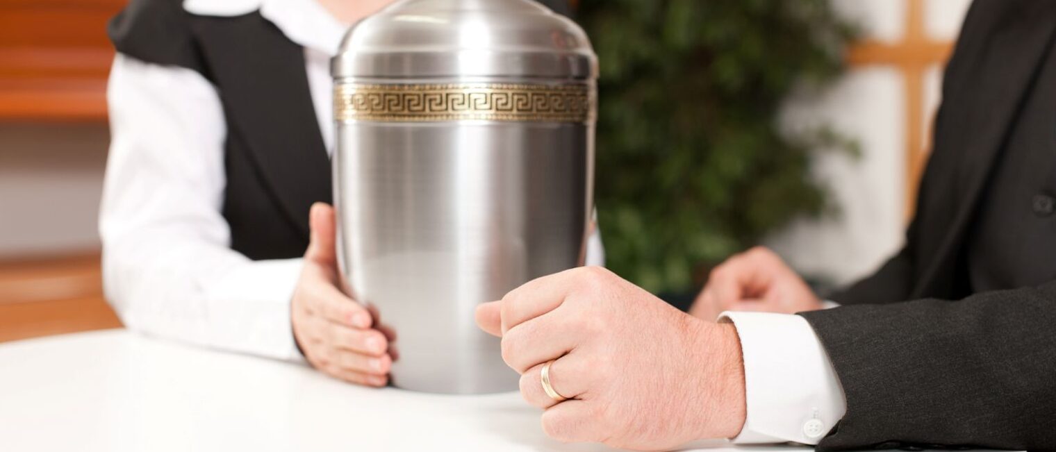 Bestatter in einem Beratungsgespräch. Auf dem Tisch eine Urne.