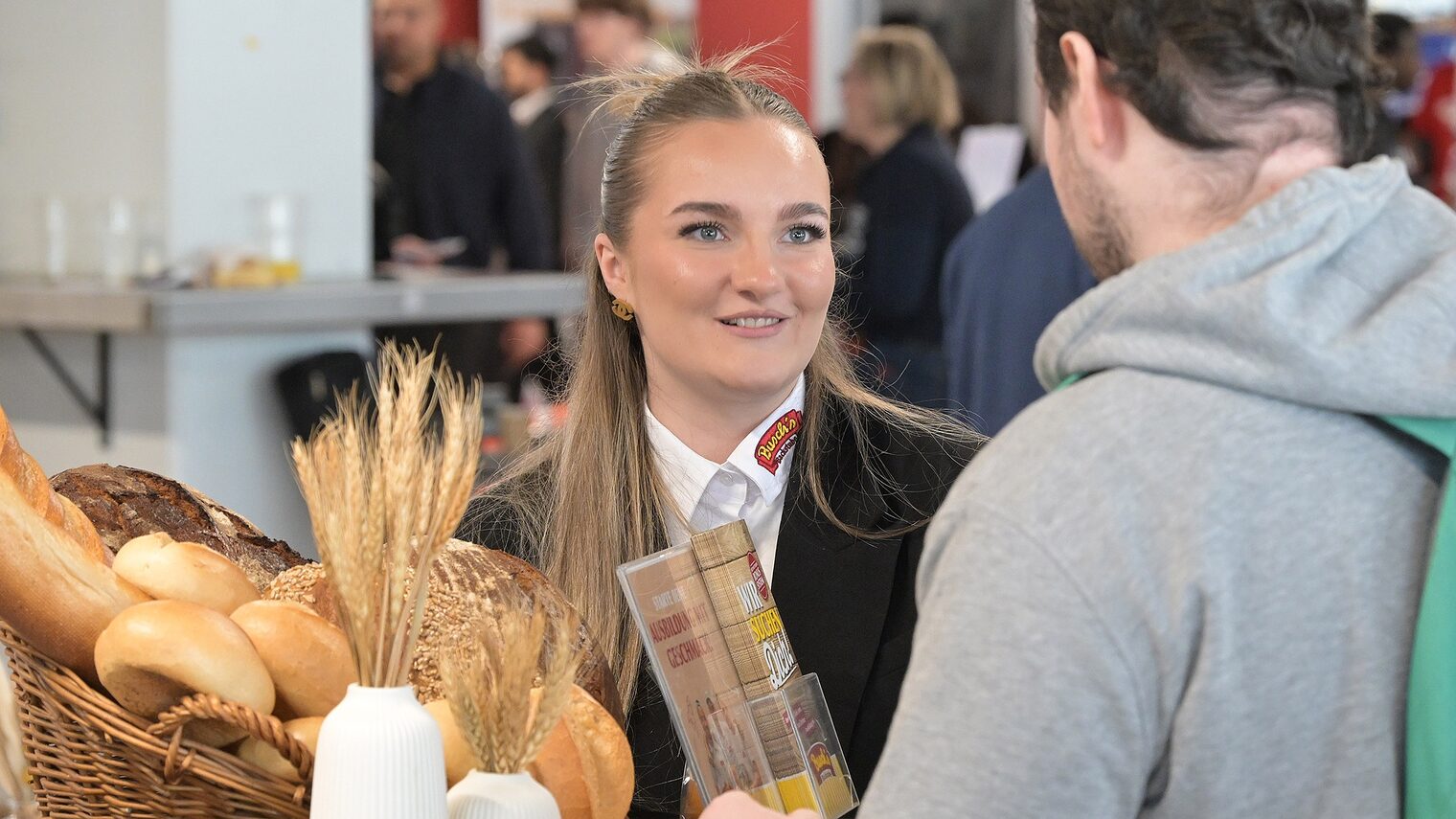 Eine Bäckerin berät einen ausbildungsplatzsuchenden Jugendlichen. Auf dem Beratungstisch steht ein Brotkorb.