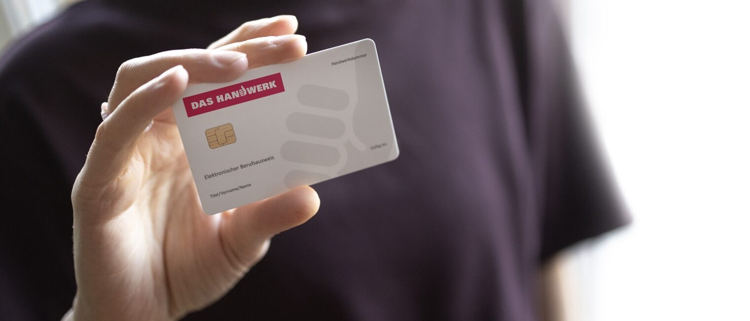 Eine Person hält die Karte des Elektronischen Berufsausweises in die Kamera. Nahaufnahme der Hand.