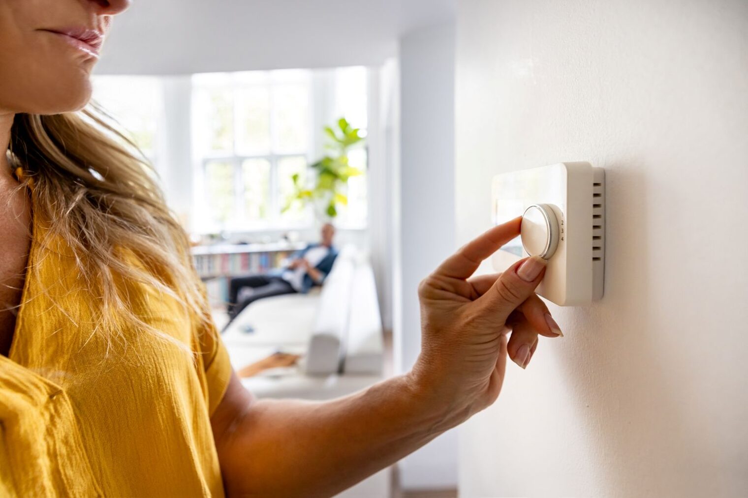 Eine Frau stellt in ihrer Wohnung die Temperatur am Heizungsregler ein.