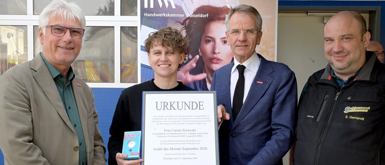 Carina Zorawski posiert mit 3 Handwerksfunktionären für ein Pressefoto. Sie zeigt ihre Auszeichnungsurkunde und eine Uhr.